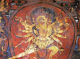 Tibet Guge 08 Tsaparang 04 Yamantaka Temple Chakrasamvara On the right wall is a four-headed, 12-armed large painting of Chakrasamvara (Tib. Demchog), embracing his consort Vajravarahi. Vajravarahi�s left hand circles Chakrasamvara�s neck while her right holds a vajra. In his right hands he holds a vajra lasso, a drum, a hatchet, a chopper and a trident; while his left hands hold the vajra lasso, a skull full of blood, a noose and the heads of Brahma. Photo - Weyer/Aschoff: Tsaparang, Tibets Grosses Geheimnis.